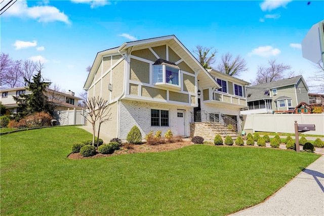 view of front of home featuring fence, stairs, a front lawn, and brick siding