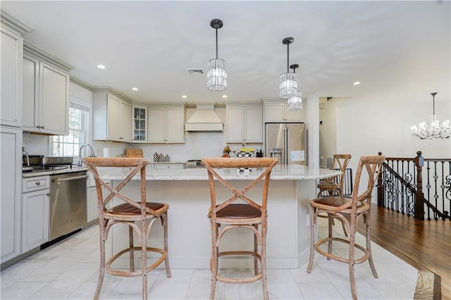kitchen featuring a center island, tasteful backsplash, light stone counters, custom exhaust hood, and stainless steel appliances