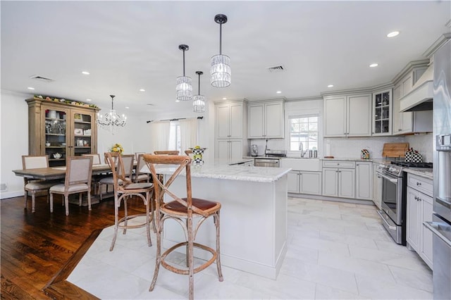 kitchen featuring a kitchen island, visible vents, appliances with stainless steel finishes, a sink, and a chandelier