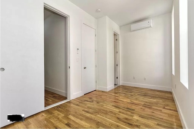 121 Lewis Ave, Brooklyn, NY 11221 - unfurnished bedroom featuring a wall unit AC, baseboards, and light wood-type flooring