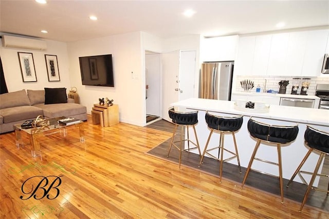 2070 Pearson St, Brooklyn, NY 11234 - kitchen featuring appliances with stainless steel finishes, a kitchen bar, a wall mounted air conditioner, white cabinetry, and light countertops