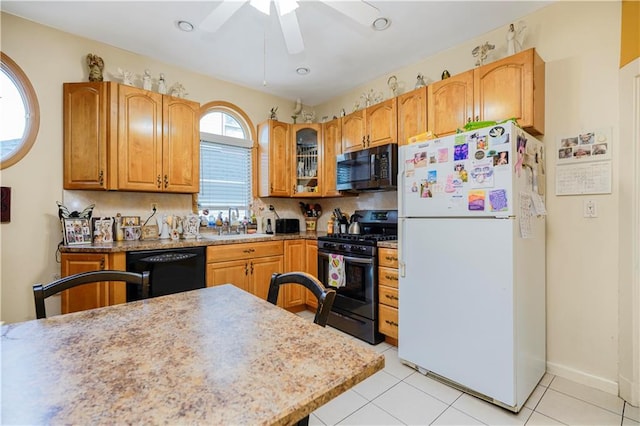 kitchen featuring black appliances, ceiling fan, a sink, glass insert cabinets, and light tile patterned floors