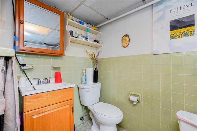 bathroom with tile walls, toilet, vanity, and wainscoting