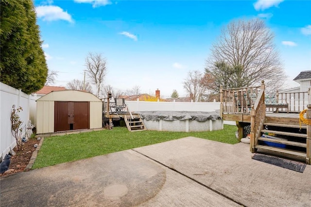 view of yard with a storage shed, a wooden deck, a patio, and an outbuilding