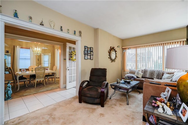 living room with a chandelier, tile patterned flooring, carpet floors, and plenty of natural light