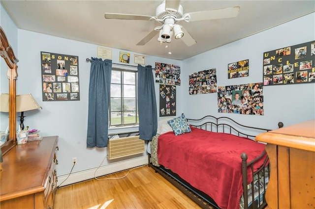 bedroom featuring a ceiling fan, baseboards, a baseboard heating unit, and wood finished floors