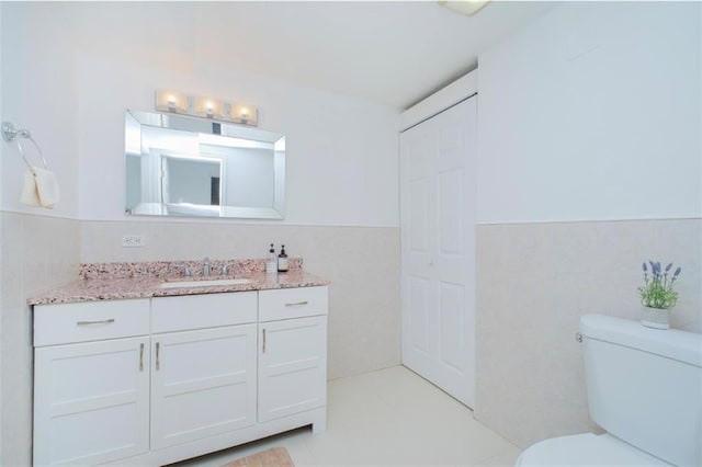 2841 Ford St Unit 1R, Brooklyn, NY 11235 - bathroom with wainscoting, tile walls, toilet, vanity, and tile patterned floors