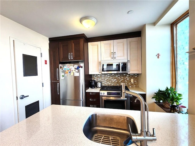 129 W End Ave Unit 3B, Brooklyn, NY 11235 - kitchen with appliances with stainless steel finishes, decorative backsplash, a sink, dark brown cabinets, and light stone counters