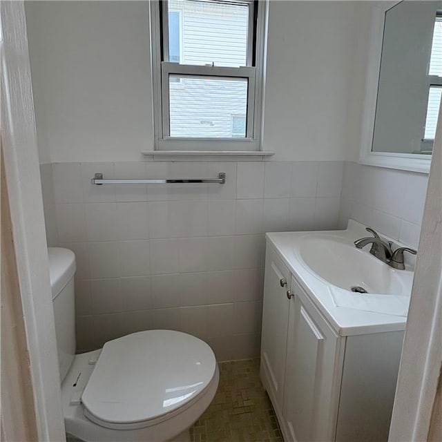 bathroom with vanity, a wealth of natural light, toilet, and tile walls