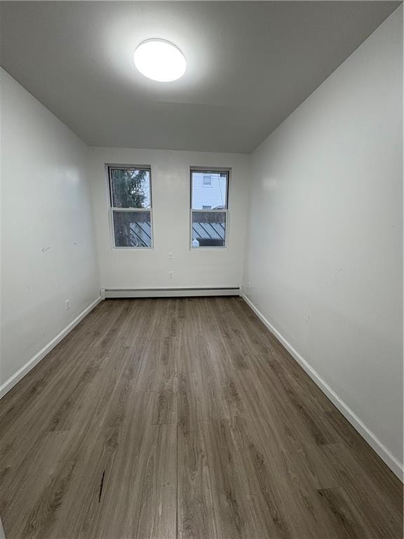 unfurnished room with baseboards, a baseboard radiator, and dark wood finished floors
