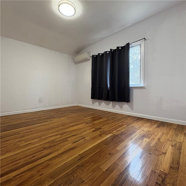 empty room with baseboards, a wall unit AC, lofted ceiling, and dark wood-type flooring