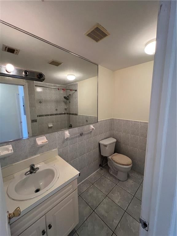 1391 Stanley Ave, East New York, NY 11208 - bathroom featuring tile walls, toilet, vanity, a tile shower, and tile patterned flooring