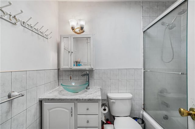 bathroom featuring a wainscoted wall, toilet, tile walls, vanity, and bathtub / shower combination