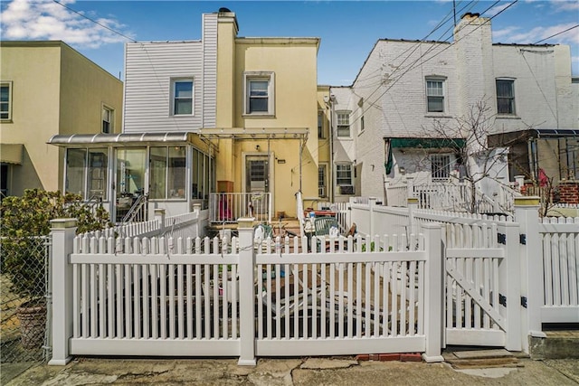 view of front facade featuring stucco siding, a fenced front yard, and a sunroom