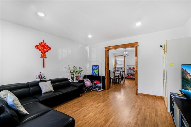 living room with baseboards, recessed lighting, an inviting chandelier, and light wood-style floors