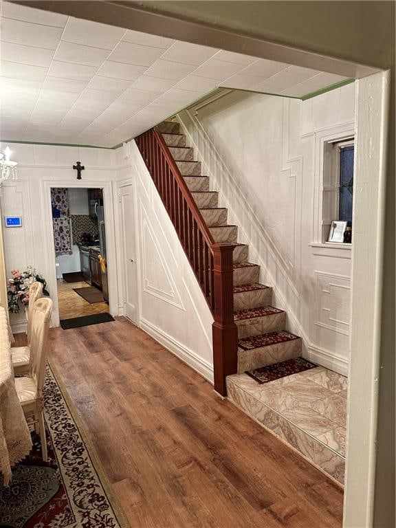 956 E 48th St, Brooklyn, NY 11203 - staircase with wood finished floors, a decorative wall, and a chandelier