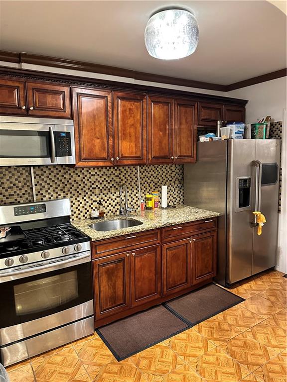 956 E 48th St, Brooklyn, NY 11203 - kitchen with appliances with stainless steel finishes, a sink, ornamental molding, tasteful backsplash, and light stone counters
