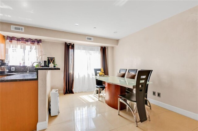 dining space featuring baseboards, visible vents, indoor wet bar, and light tile patterned floors