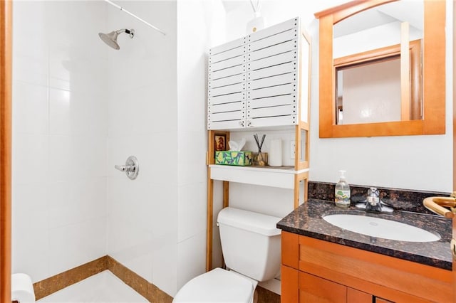 full bath with toilet, vanity, and a tile shower