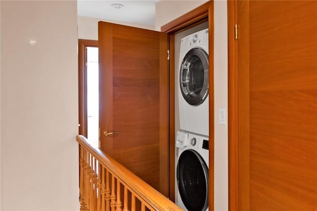 clothes washing area featuring stacked washer and dryer and laundry area