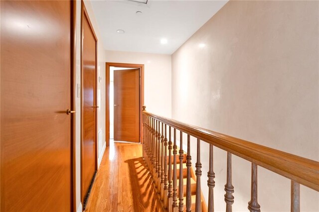 corridor with an upstairs landing and light wood-style floors