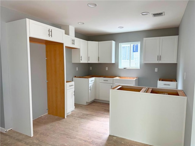 kitchen with white cabinets, recessed lighting, visible vents, and light wood-style floors