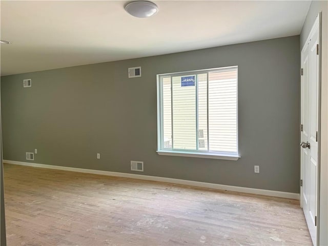 empty room featuring baseboards, light wood-style flooring, and visible vents