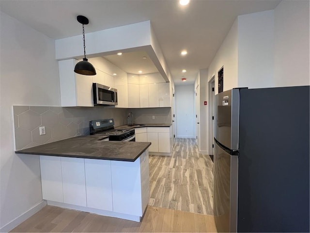 800 5th Ave Unit 4A, Brooklyn, NY 11232 - kitchen with stainless steel appliances, dark countertops, a sink, light wood-style floors, and a peninsula