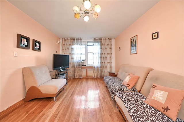 living room with light wood finished floors, a notable chandelier, and baseboards