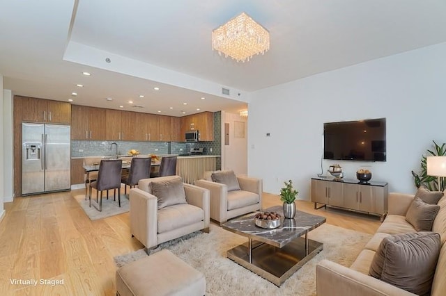 living room featuring light wood-style floors, recessed lighting, and a chandelier
