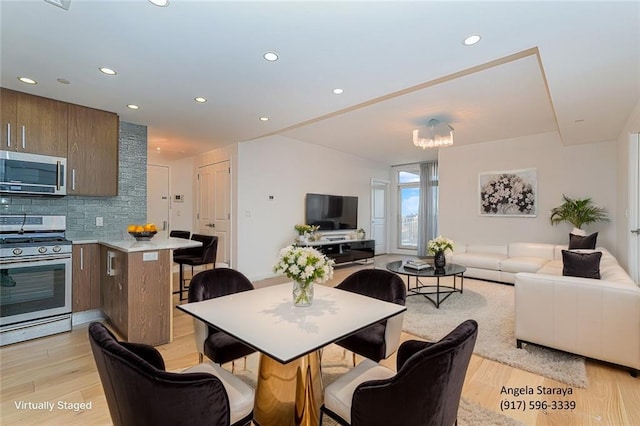 dining space featuring light wood-style floors, recessed lighting, and a chandelier