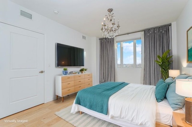 bedroom featuring a chandelier and light wood finished floors