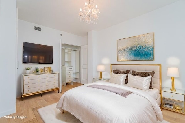 bedroom with light wood-style flooring, a chandelier, and a closet