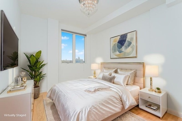 bedroom featuring light wood finished floors and a chandelier