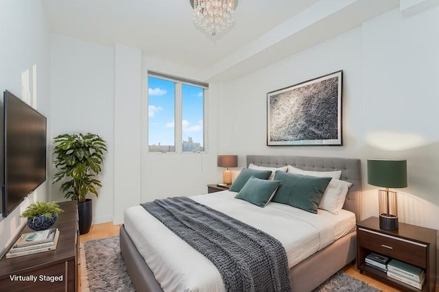 bedroom with a chandelier, wood finished floors, and baseboards