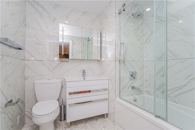 full bath with tile walls, combined bath / shower with glass door, toilet, and vanity