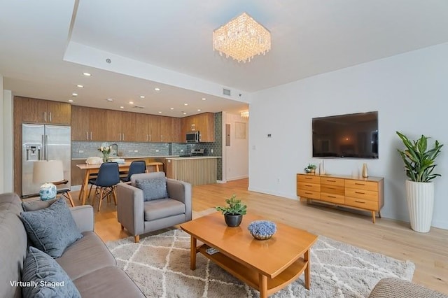 living room featuring recessed lighting, light wood finished floors, baseboards, and a chandelier