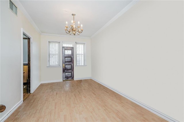 spare room with wood finished floors, ornamental molding, baseboards, visible vents, and a notable chandelier