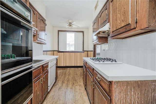 2567 E 6th St, Brooklyn, NY 11235 - kitchen featuring white appliances, under cabinet range hood, light wood finished floors, wainscoting, and ceiling fan