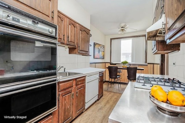 kitchen with ceiling fan, double wall oven, stainless steel countertops, dishwasher, and backsplash