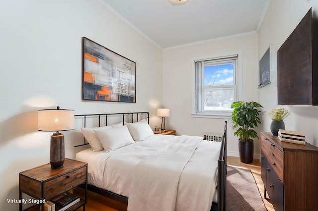 bedroom with ornamental molding, radiator, and wood finished floors