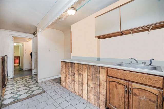 kitchen featuring brown cabinets, light countertops, and a sink