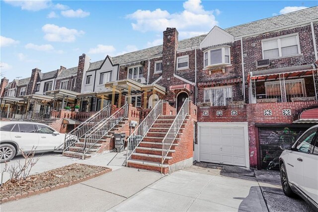 multi unit property with driveway, a high end roof, a residential view, brick siding, and a garage