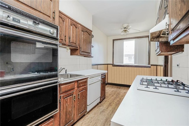 kitchen featuring a sink, white appliances, light wood-type flooring, a ceiling fan, and light countertops