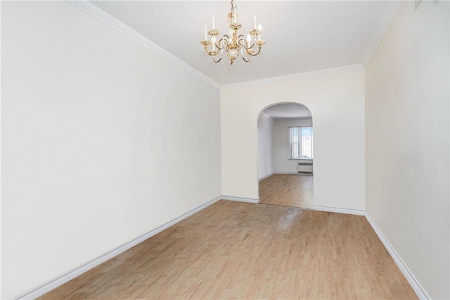 unfurnished room featuring a chandelier, crown molding, baseboards, arched walkways, and wood finished floors