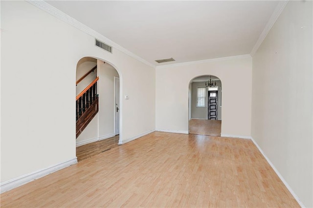 empty room featuring arched walkways, wood finished floors, stairway, ornamental molding, and visible vents