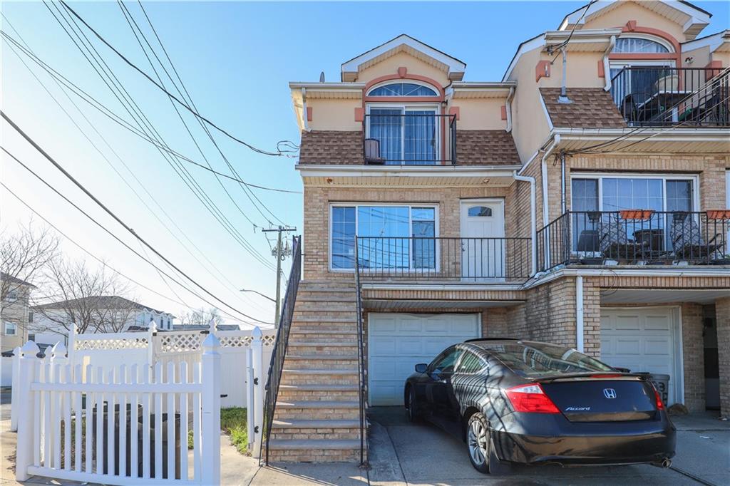 985 Father Capodanno Blvd, Staten Island, NY 10306 - view of property with a garage, fence, stucco siding, brick siding, and concrete driveway