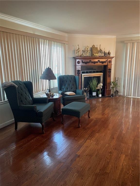 sitting room with a fireplace, ornamental molding, and wood finished floors