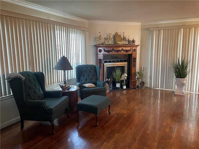 living area featuring crown molding, baseboards, a fireplace, and wood finished floors