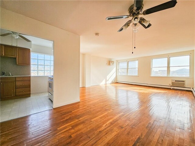 unfurnished living room featuring ceiling fan, wood-type flooring, and a wealth of natural light